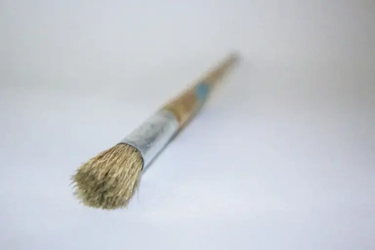 Close-up of a natural-bristle paintbrush resting on a white surface, ready for fabric painting