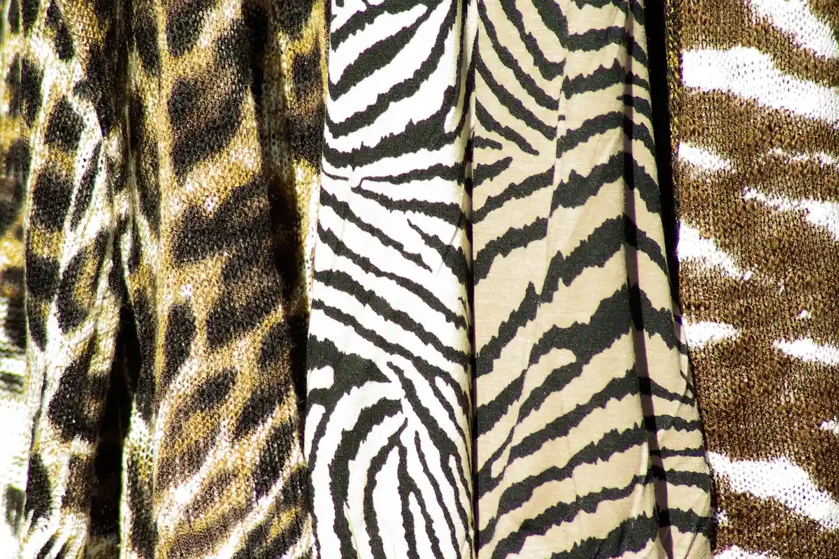 Close-up of folded animal-print fabrics featuring zebra and tiger patterns.