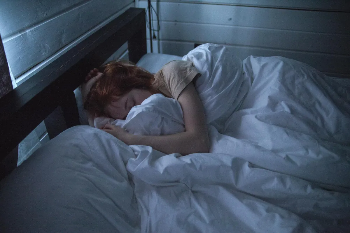 A person sleeping in a bed with white bamboo viscose sheets in a blue-toned room