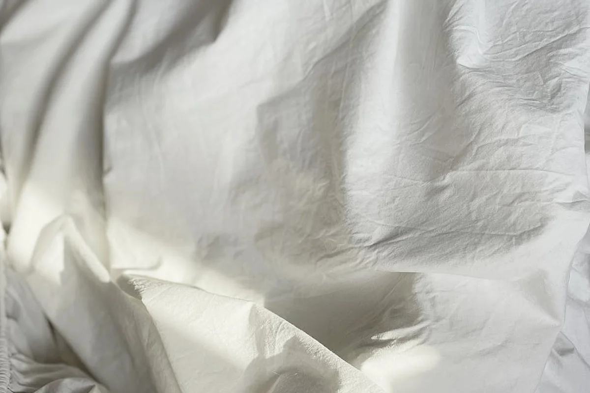 Close-up of crumpled white bedsheets showing fabric texture and weave details