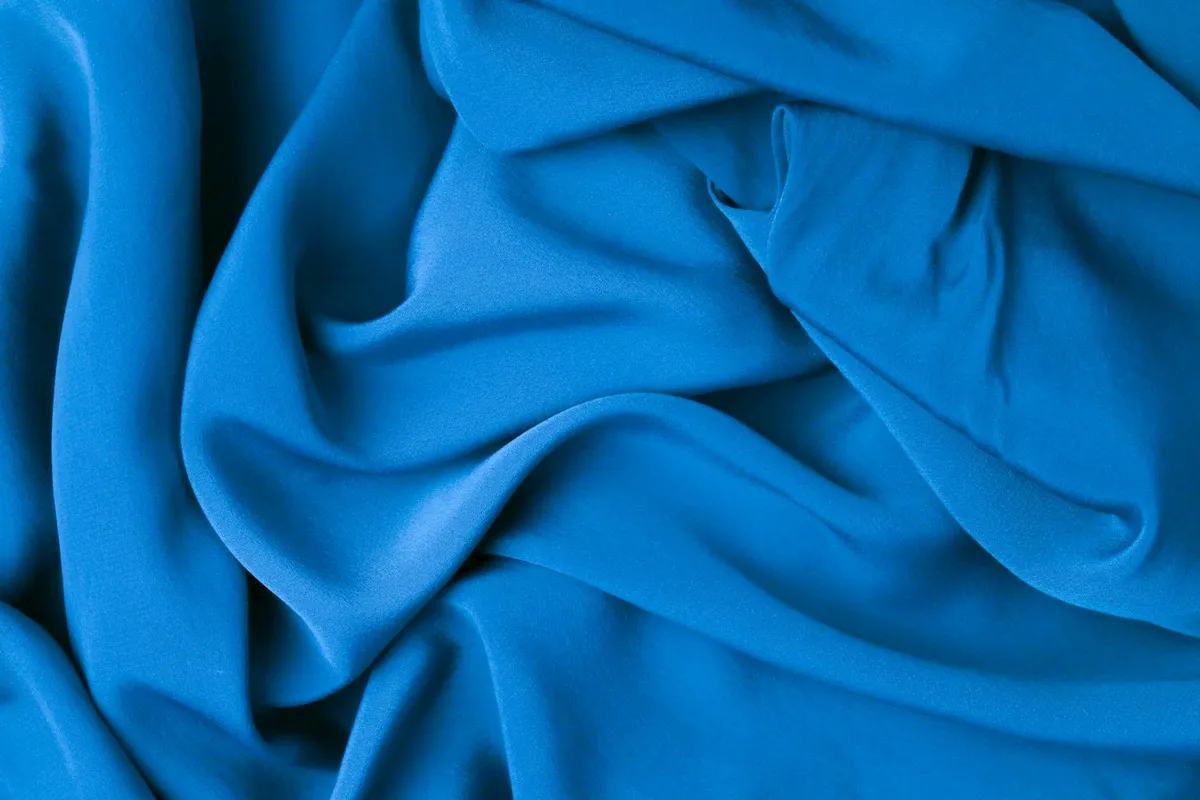 Close-up of bright blue viscose and rayon fabric with soft folds
