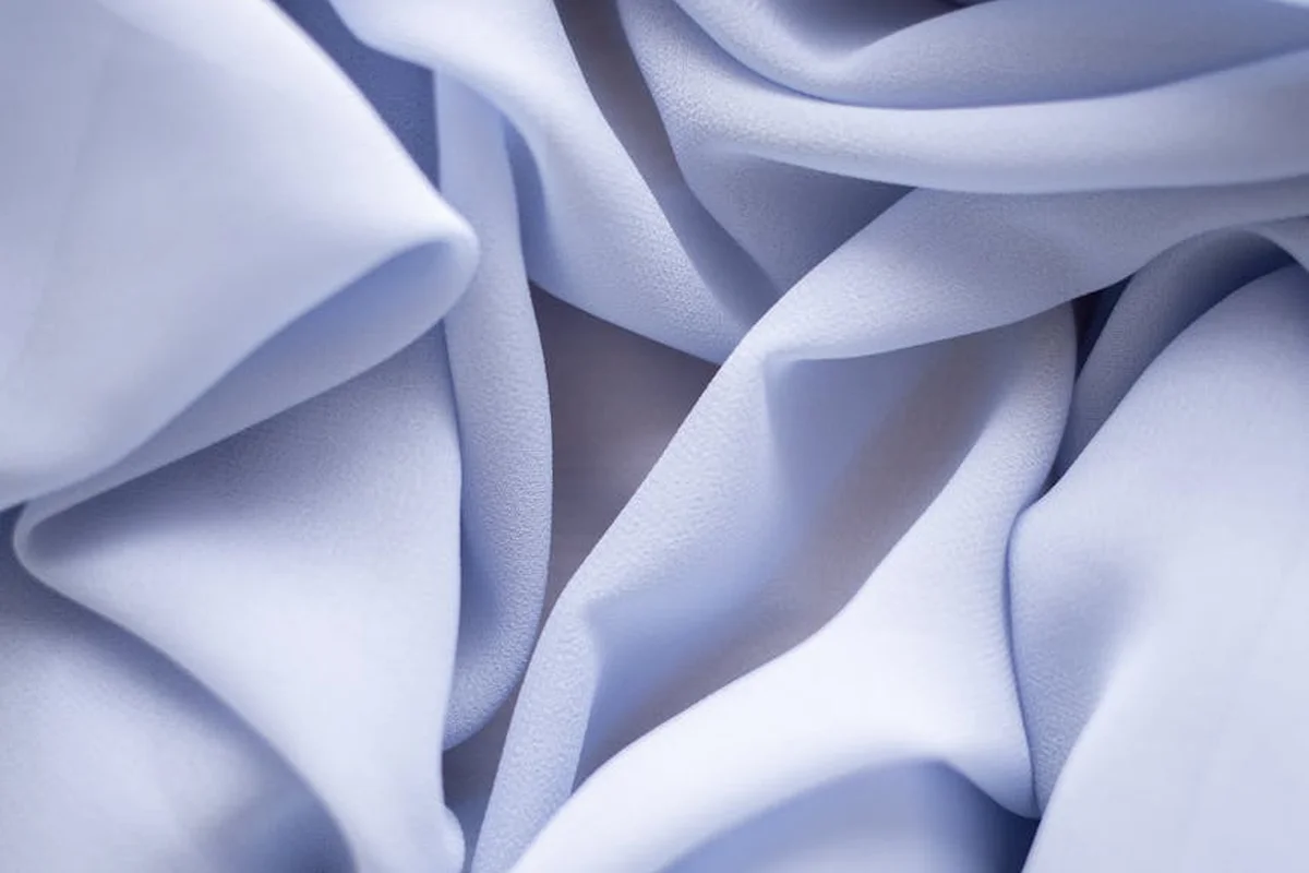 Close-up of smooth, light-blue fabric folds with silky texture.