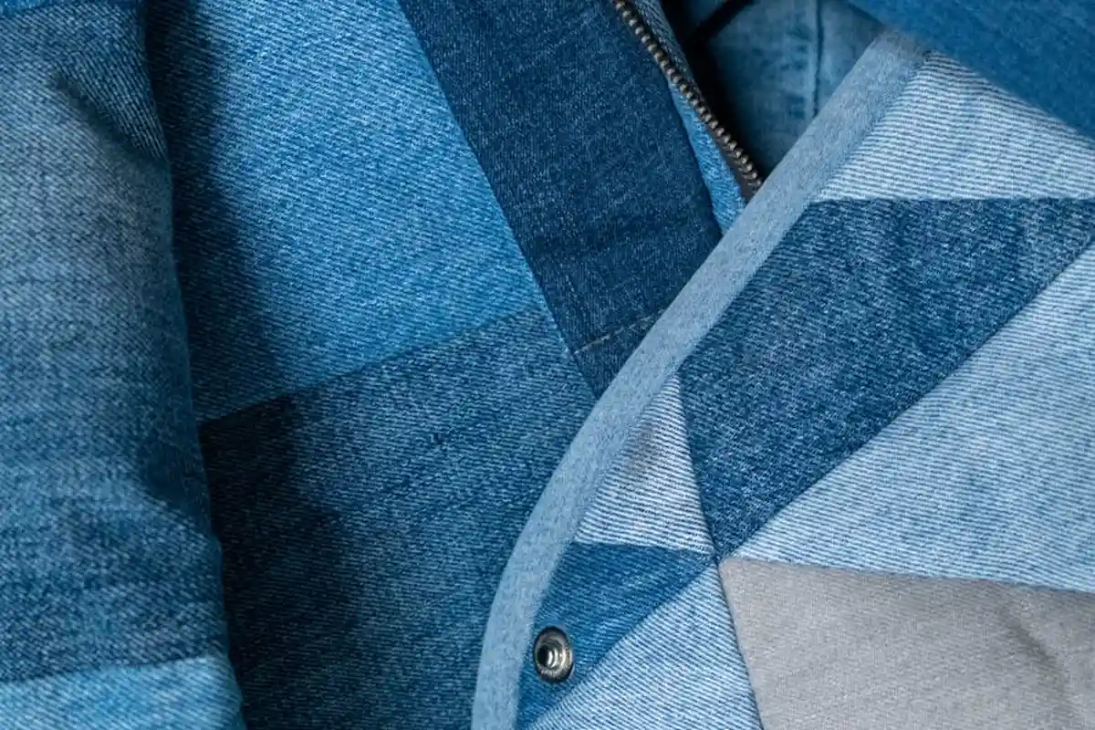 Close-up of blue patchwork cotton fabric with geometric panels and visible stitching.