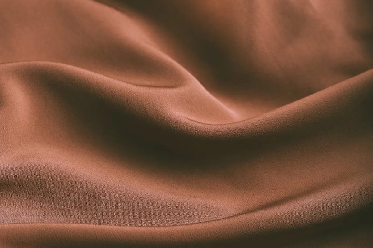 Close-up of brown fabric with flowing folds and soft texture.