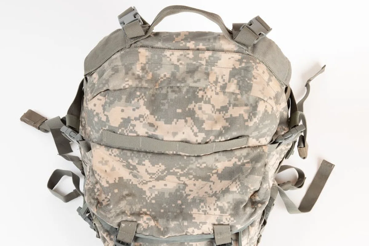 Camouflage nylon backpack with multiple straps and webbing.