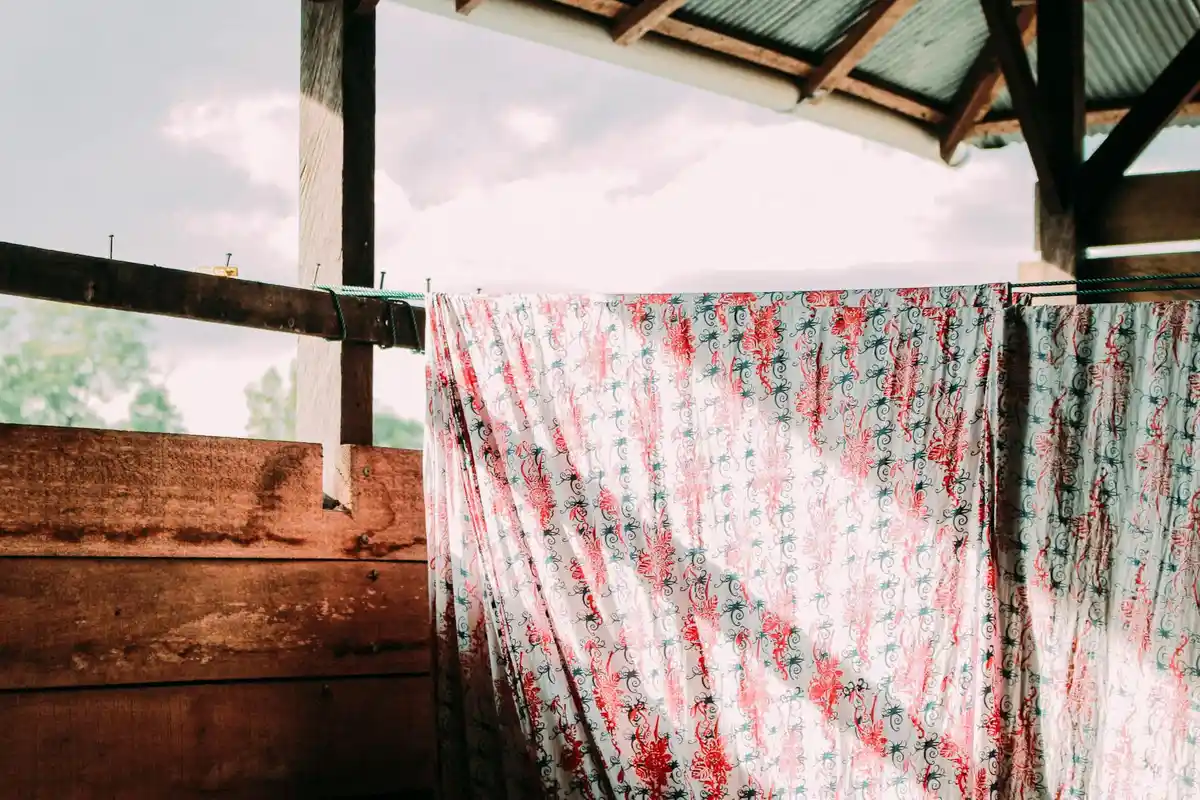 Clothesline with striped fabric drying under a wooden shelter, illustrating outdoor textile drying and moisture behavior.