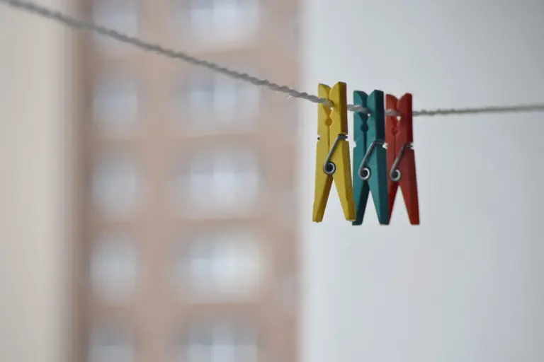 Colorful clothespins on a clothesline with a blurred city-building backdrop