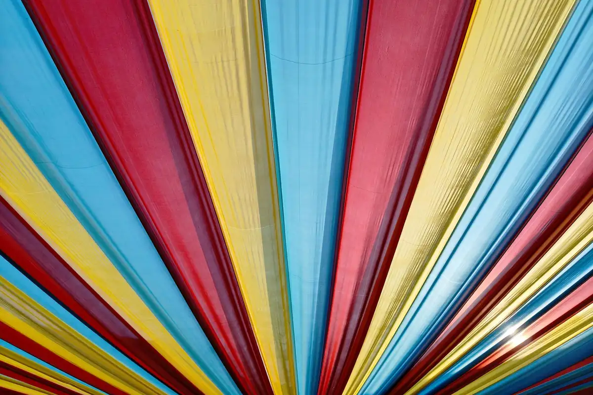 Vibrant fabric ribbons in blue, red, yellow, and gold radiating from a center point.