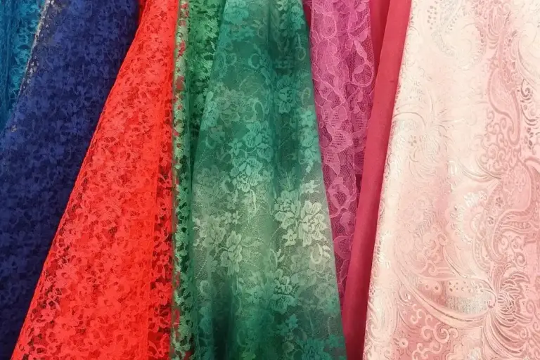 Rows of colorful lace fabric swatches in blue, red, green, purple, pink, and cream.