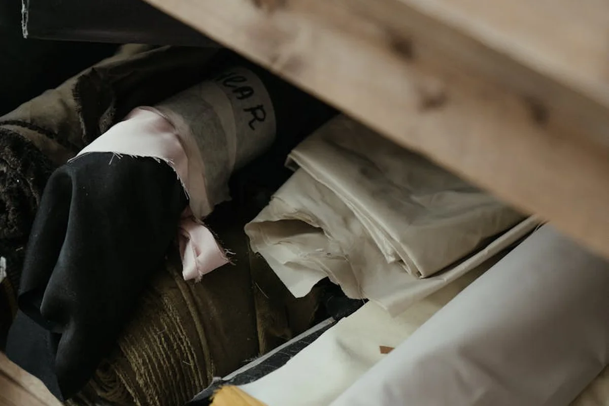 Close-up of assorted fabric swatches and folds tucked into a storage drawer, showing a mix of textures and colors