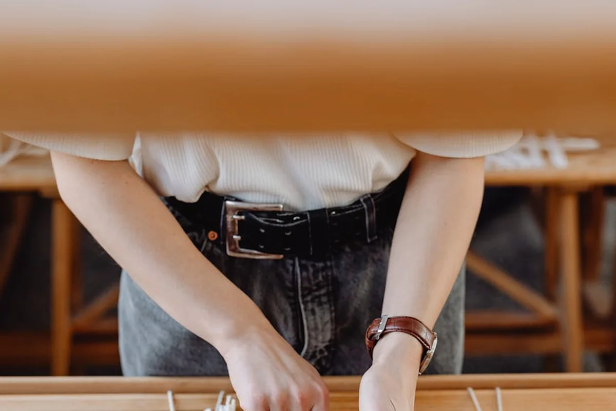 Hands of a worker guiding a loom to weave cotton fabric