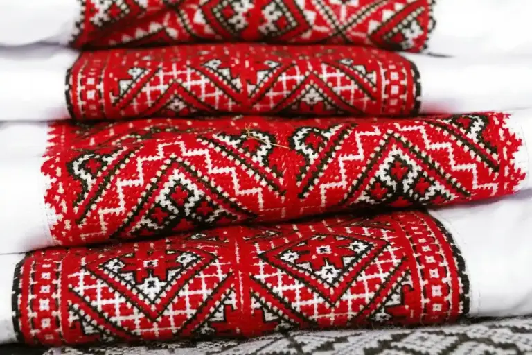 Close-up of stacked red and white embroidered cotton fabric with geometric patterns