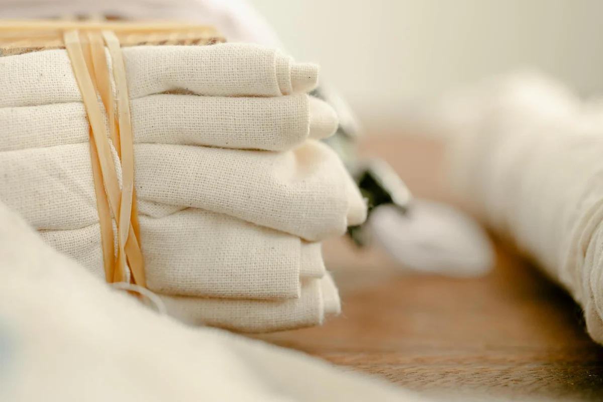 Stack of folded natural cotton fabric tied with a string on a wooden surface.