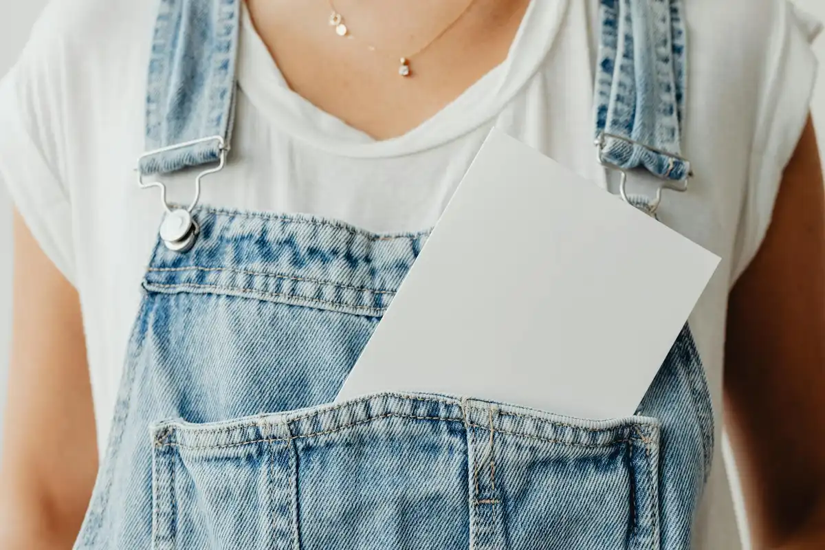 Denim overalls with a white card tucked into the front pocket, representing cotton fabric in a testing context.