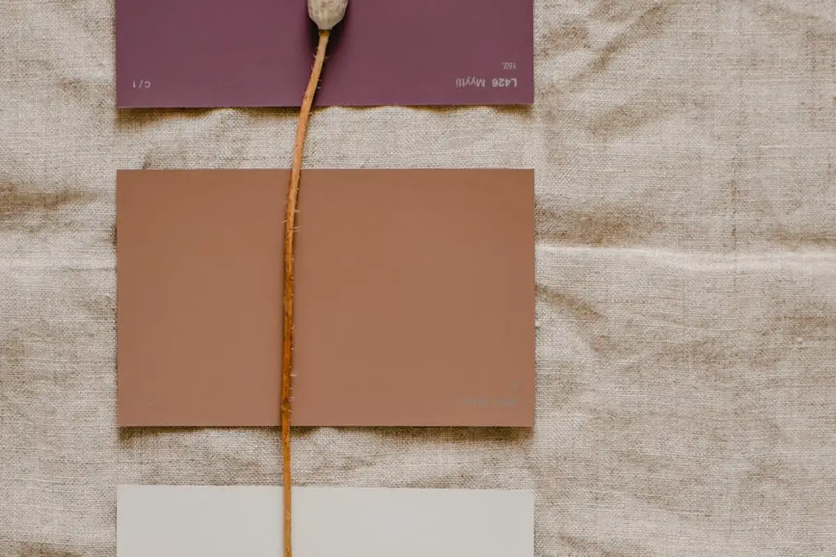 Three fabric swatches in earthy tones arranged on a natural linen background, with a string running vertically between them.
