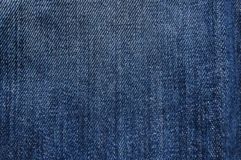 Close-up of blue denim fabric showing diagonal twill weave texture.