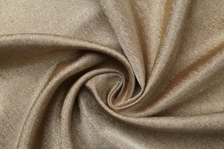 Silky beige rayon/viscose fabric swirled into a soft twist, showing drape and sheen.