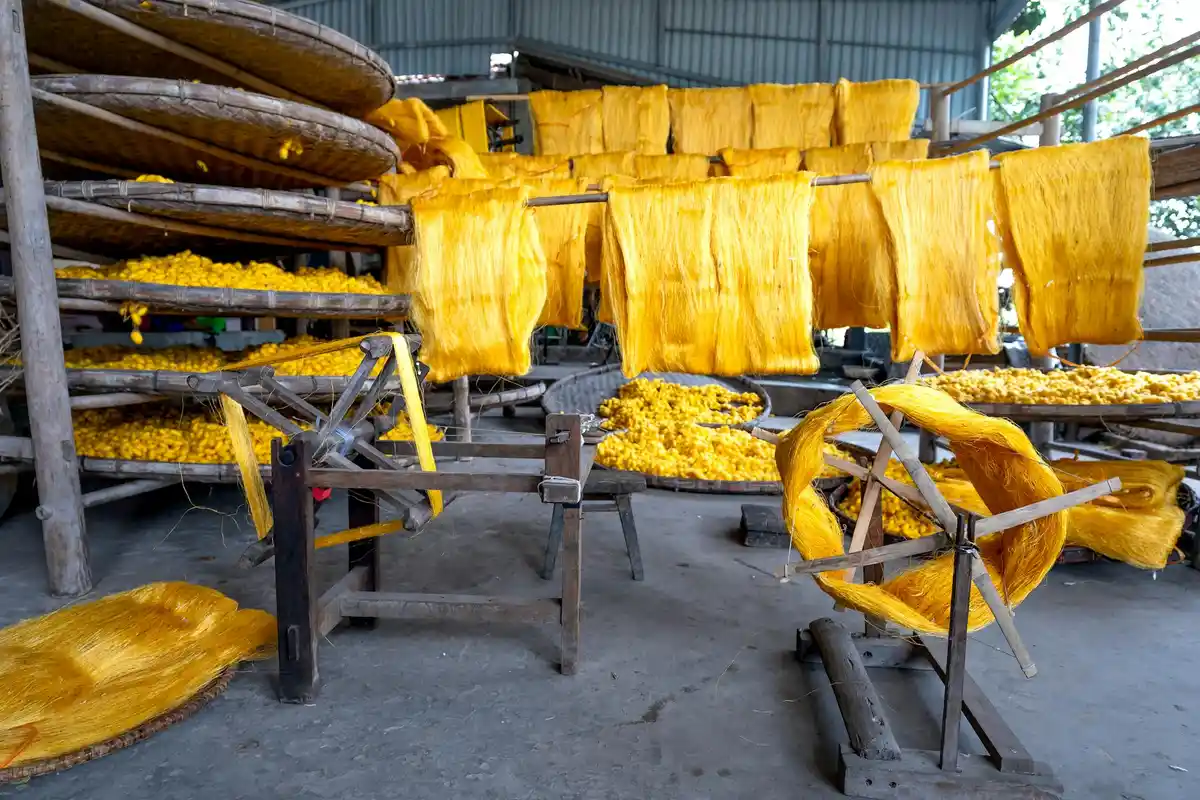 Yellow fabrics drying on racks in an industrial textile dyeing facility.