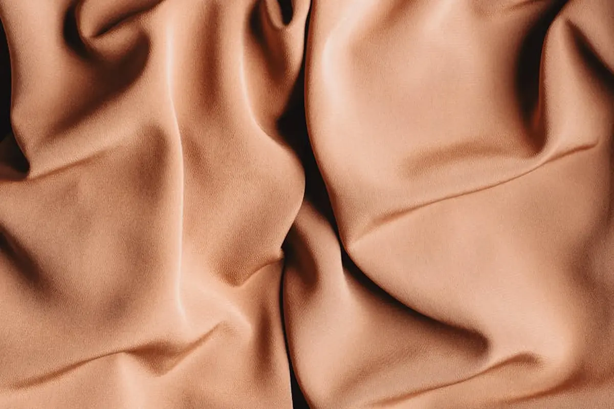 Close-up of peach-colored fabric with soft folds, illustrating blended fabrics and dyeing complexity.