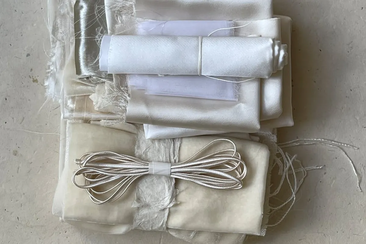Bundles of folded white and cream fabric tied with string, stacked in a tidy pile.