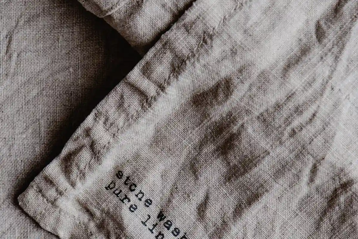Close-up of beige woven fabric with visible texture and a small, partially legible printed label