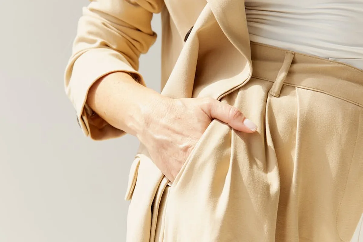 Close-up of a person wearing a beige suit with one hand in the pocket