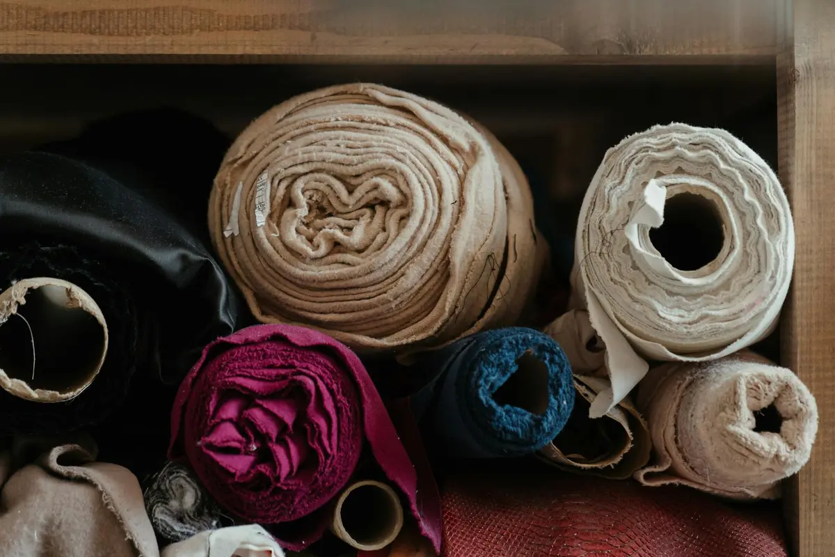 A collection of rolled cotton and rayon fabrics in a variety of colors stored in a box.