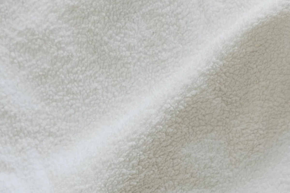 Close-up of beige fleece-like fabric texture with soft, looped fibers