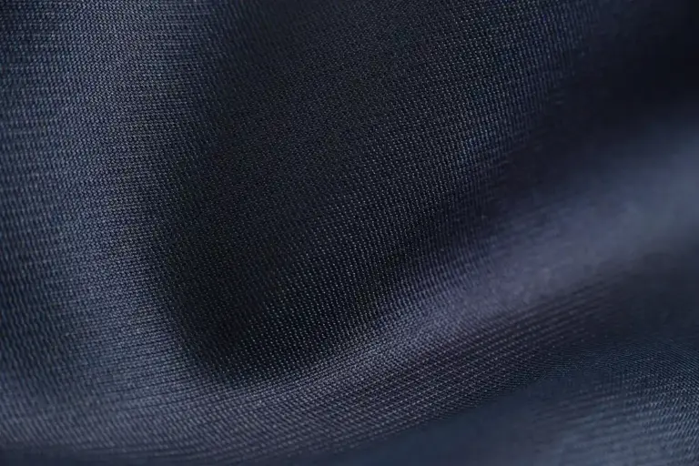 Close-up image of dark blue fabric with a smooth weave and soft folds