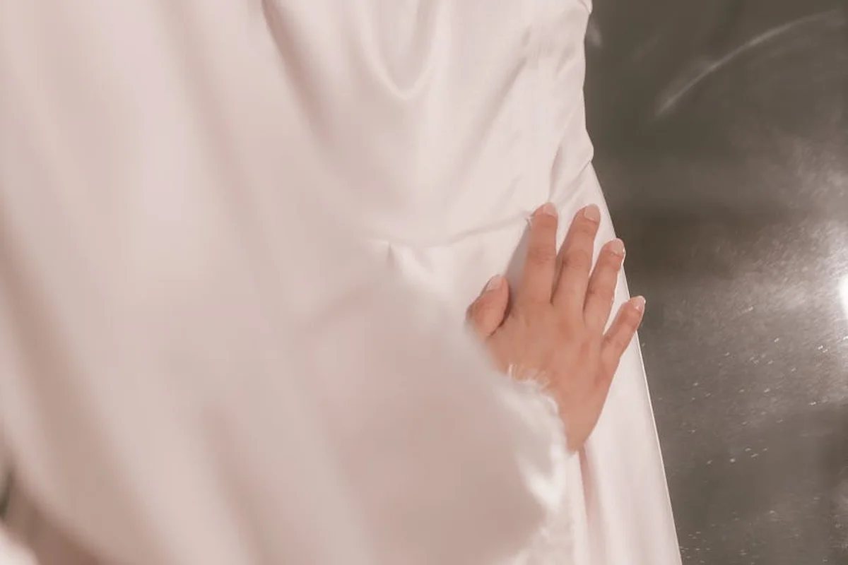 Close-up of a hand pressing a smooth white fabric, highlighting texture and drape