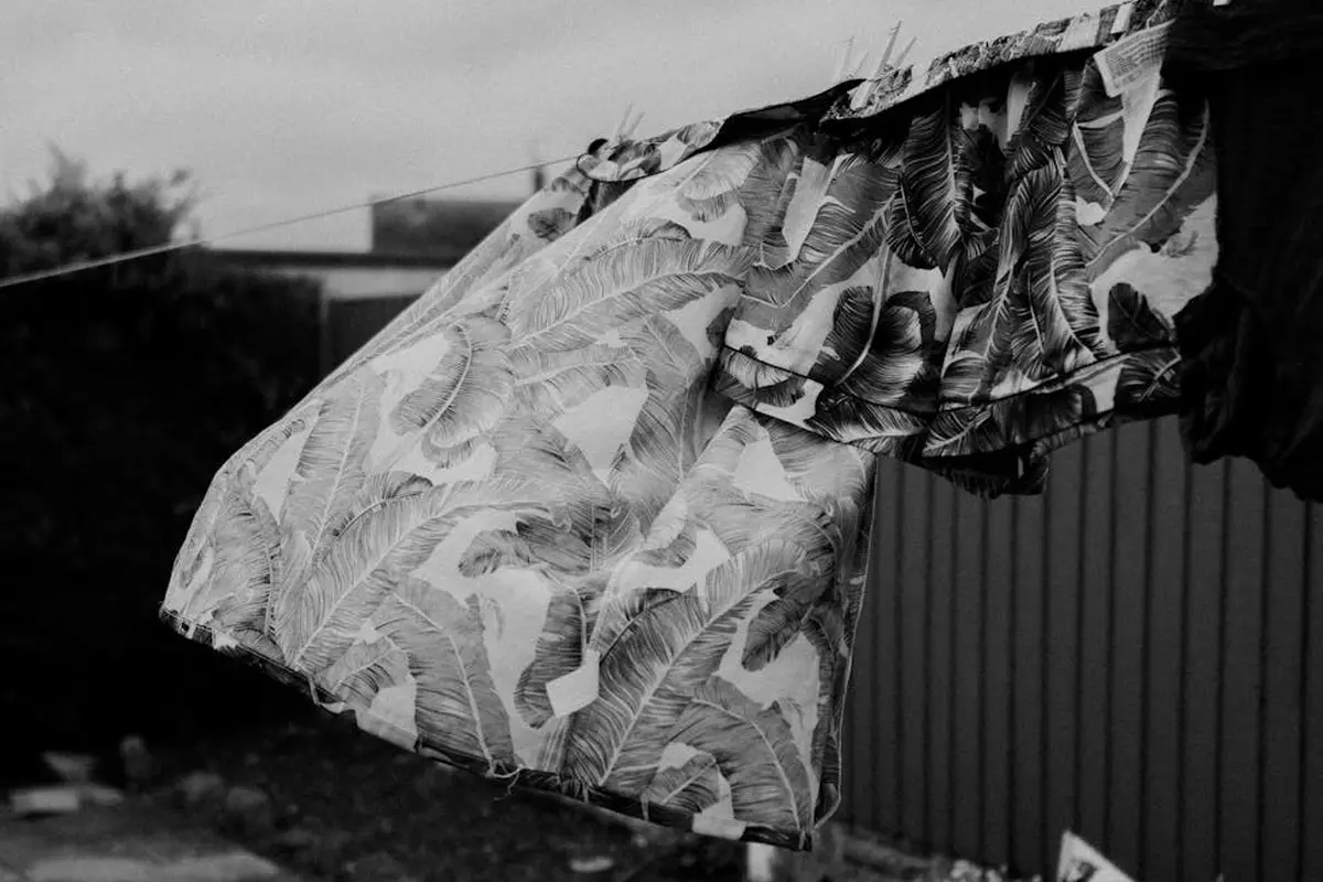 Black-and-white photograph of patterned fabric hanging on a clothesline, showing folds and texture.