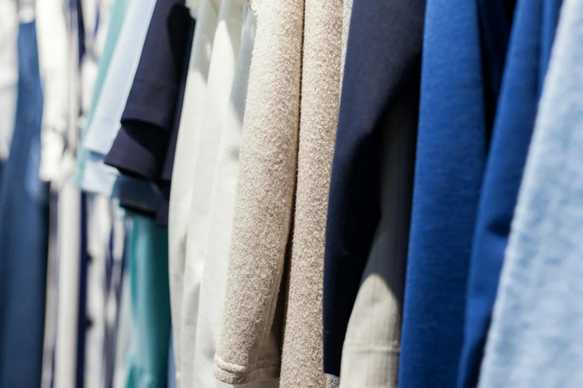 Close-up of a rack of assorted fabrics in blue, beige, and gray tones, highlighting different textures