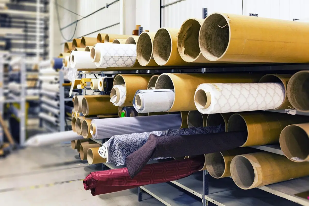 Rows of fabric rolls on shelving in a textile warehouse.