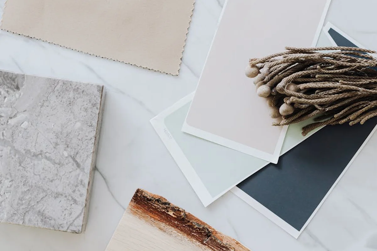 Flat lay of fabric swatches and color sample cards on a light marble surface