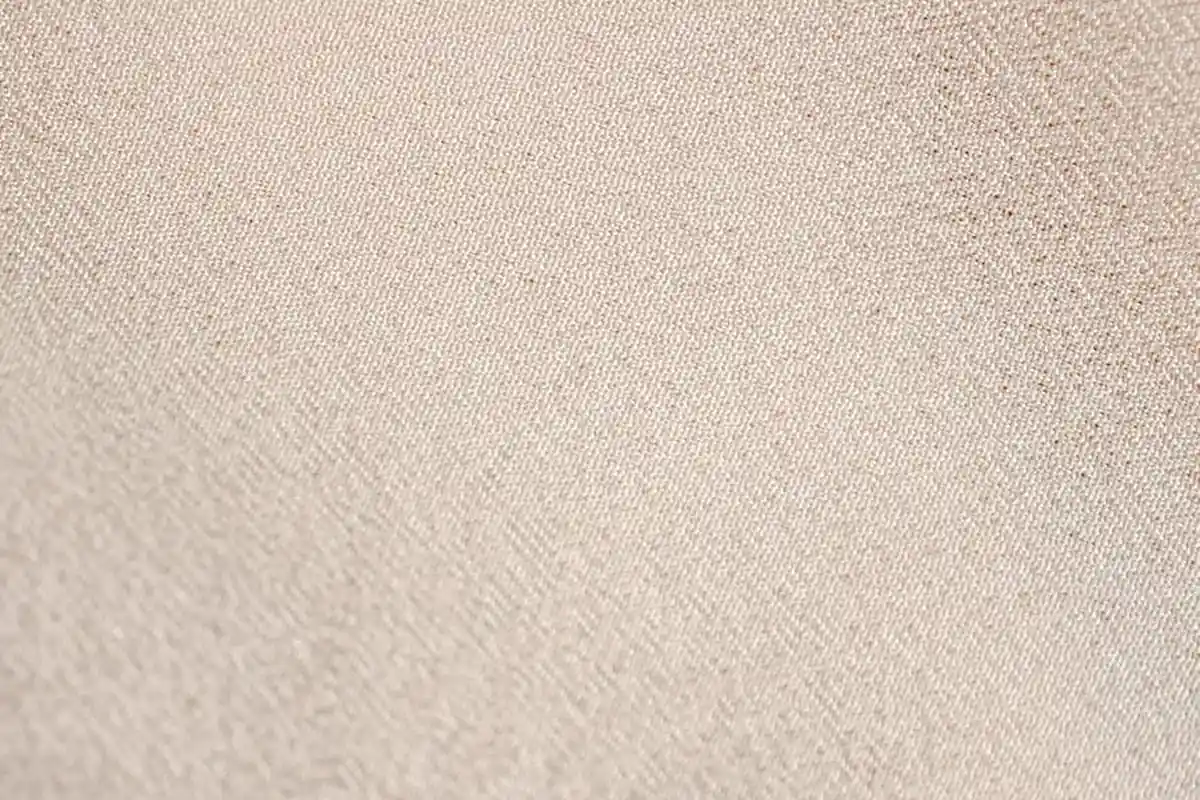 Close-up of beige textile weave texture showing alternating over-under threads.