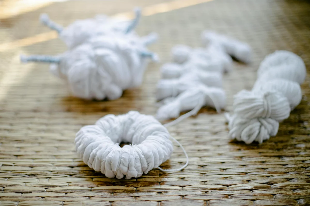 Close-up of white yarn bundles arranged on a woven straw mat, illustrating fabric samples for a risk assessment in textile safety.