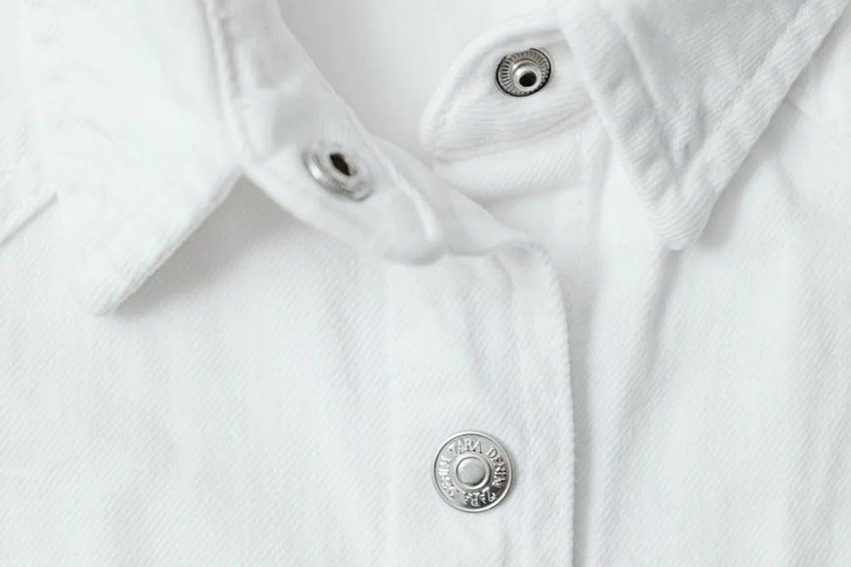 Close-up of white fabric with metal snap buttons, highlighting textile fibers