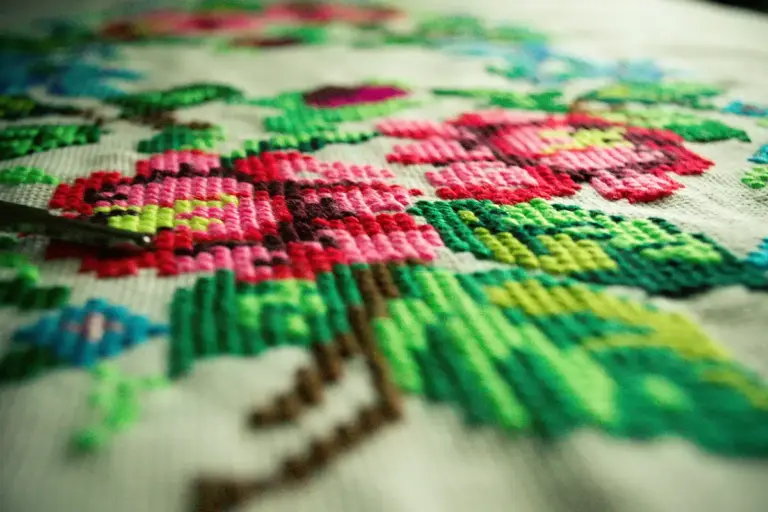 Close-up of colorful floral embroidery on fabric, featuring pink flowers and green leaves