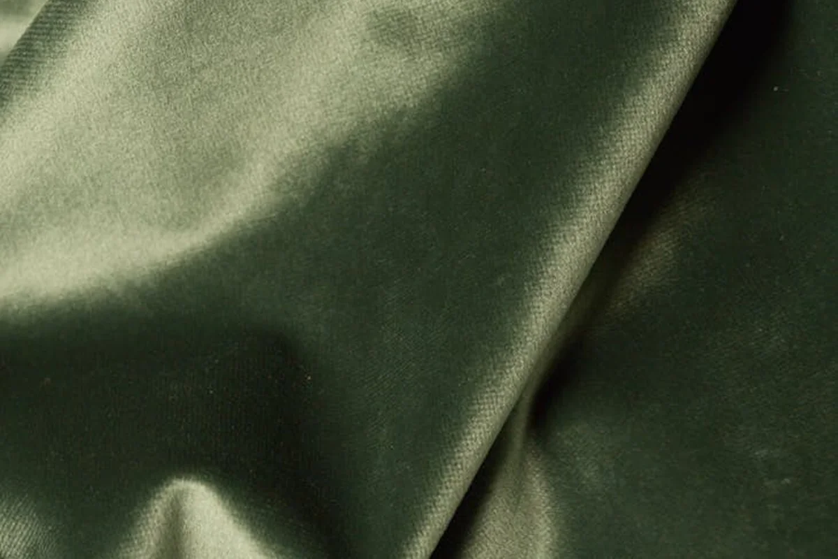 Close-up of green silk fabric with a smooth, glossy surface and soft folds