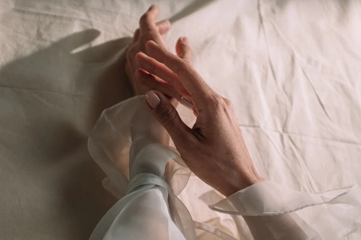 Close-up of hands handling sheer modal fabric on a white surface.