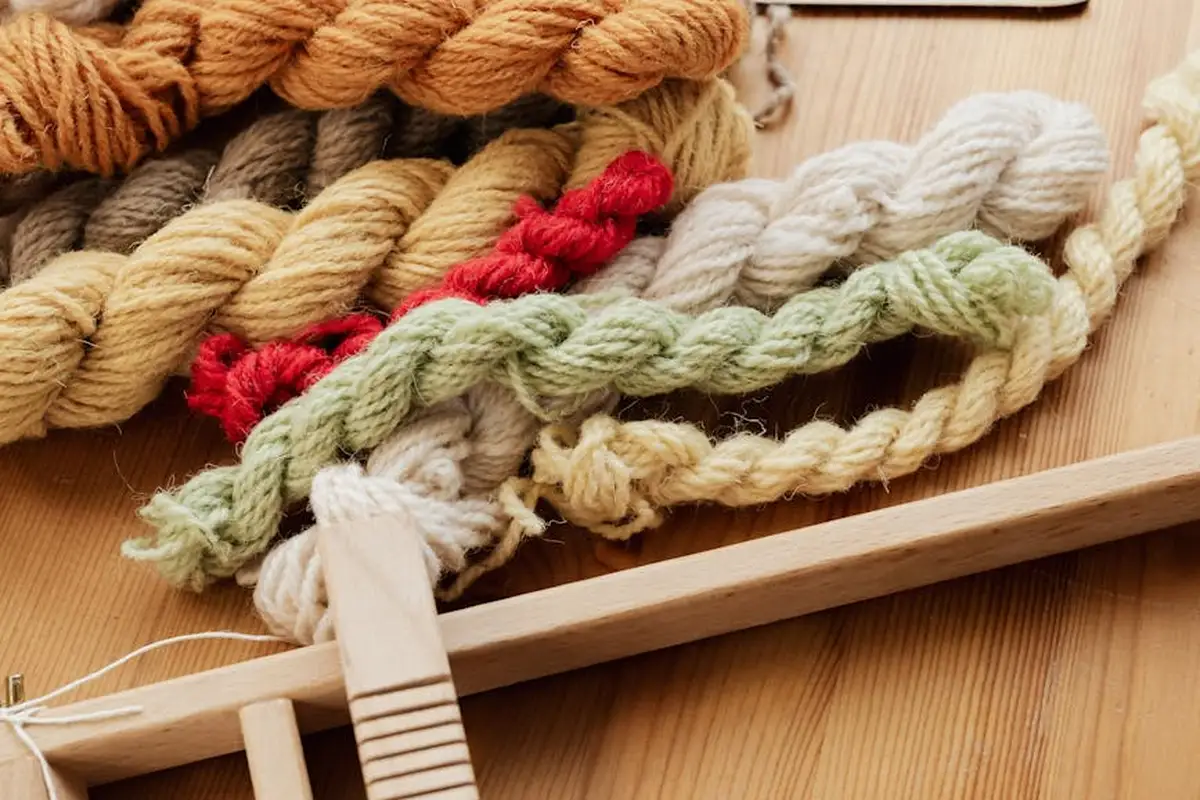 Colorful skeins of wool arranged on a wooden surface with a felting tool, illustrating intentional felting techniques.