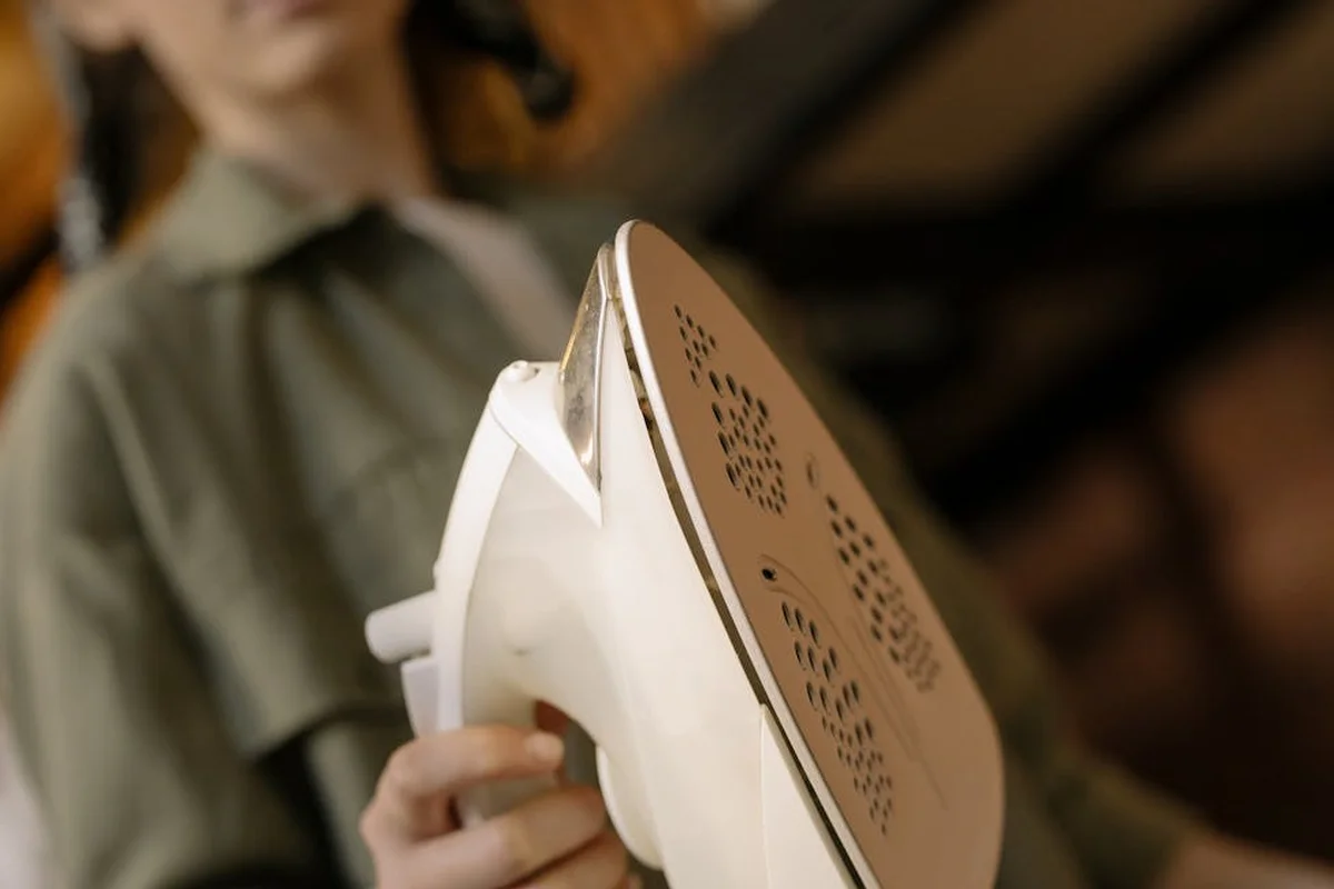 Close-up of a handheld iron being held with a blurred background