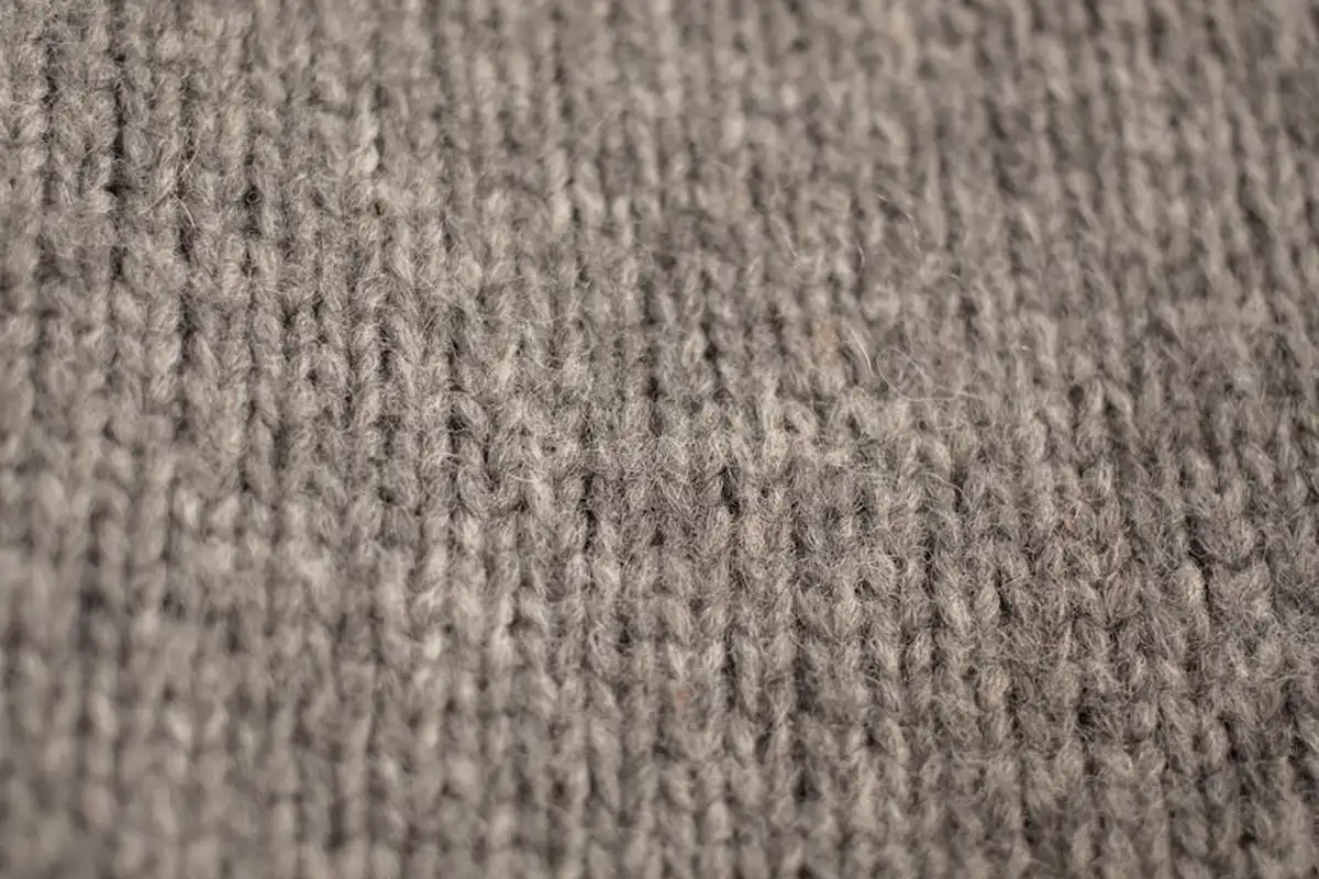 Close-up of gray knitted fabric showing interlocking yarn loops.