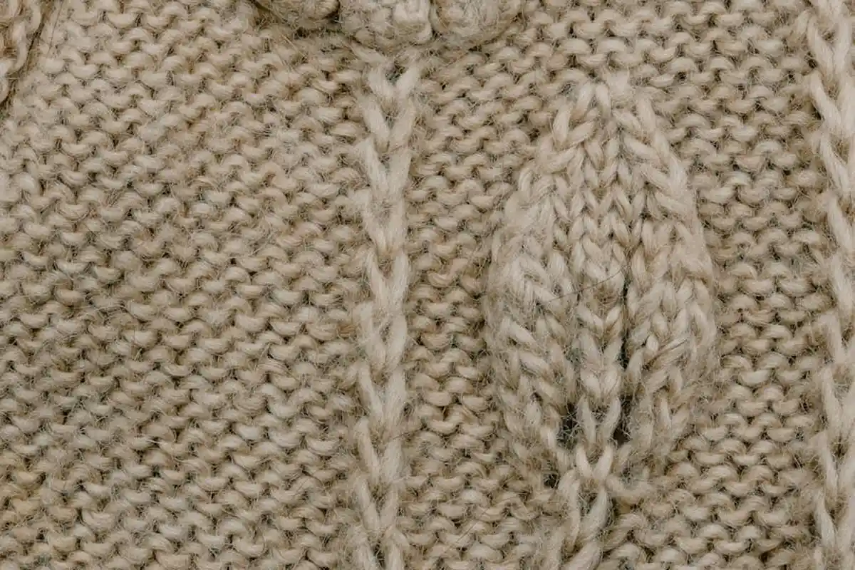 Close-up of beige knitted fabric showing textured stitches and ribbing