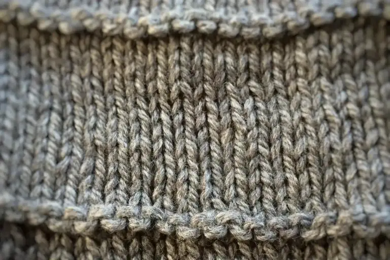 Close-up of gray rib-knit fabric showing interlocking loops and textured stitches.