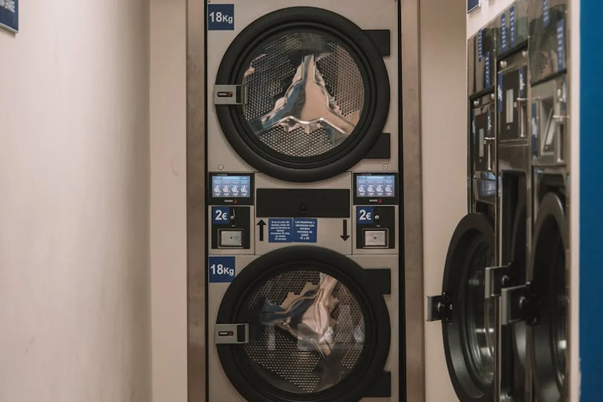 Stacked front-loading washing machines with circular doors in a laundromat.