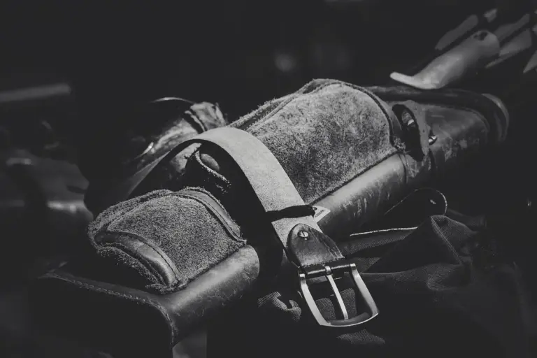 Close-up of a textured leather strap with a metal buckle in grayscale.