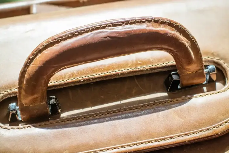 Close-up of a brown leather bag handle with visible stitching and natural grain.