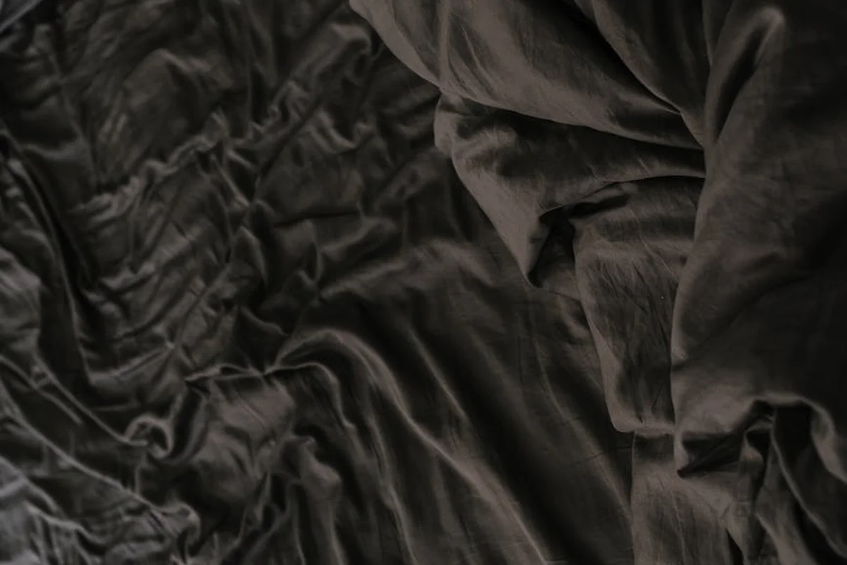 Close-up of dark, wrinkled linen fabric showing its texture and drape