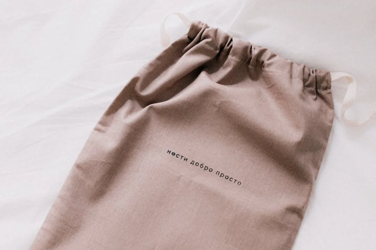 Beige drawstring bag on white fabric, illustrating careful handling to prevent fabric fraying in sewing and laundering.